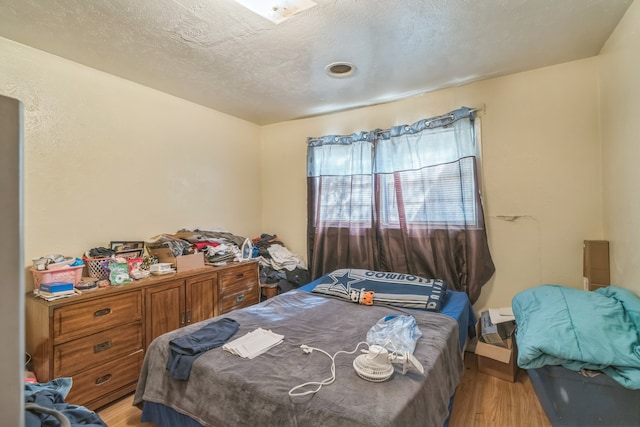 bedroom featuring light hardwood / wood-style floors and a textured ceiling