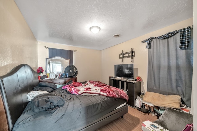 bedroom featuring hardwood / wood-style flooring and a textured ceiling