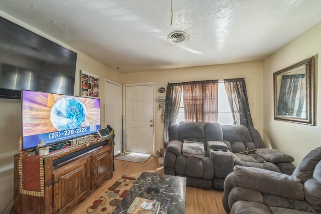 living room with a textured ceiling and light wood-type flooring