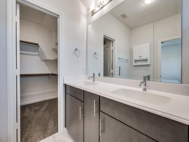 full bath with a walk in closet, double vanity, visible vents, and a sink