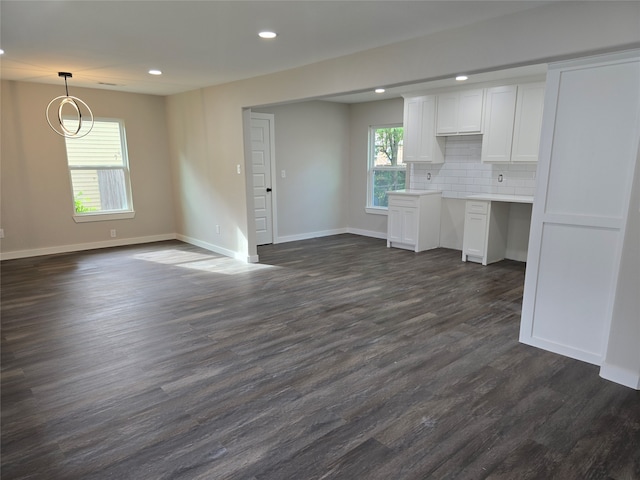 unfurnished living room featuring plenty of natural light and dark wood-type flooring