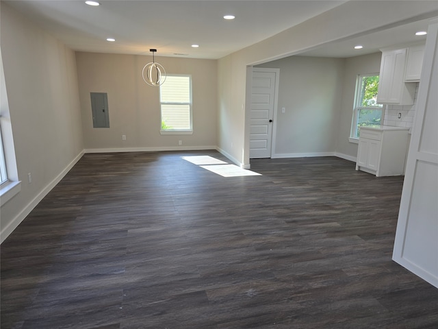 unfurnished dining area featuring dark wood-type flooring, electric panel, and plenty of natural light