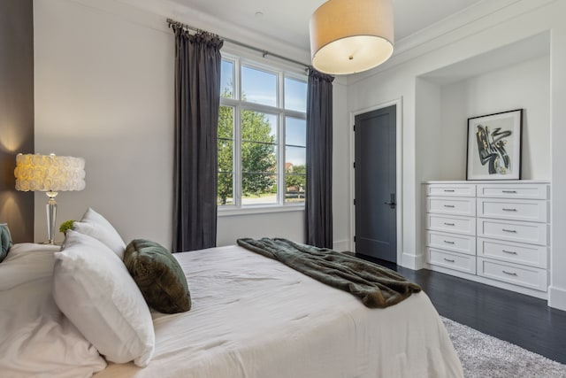 bedroom featuring crown molding and dark wood-type flooring