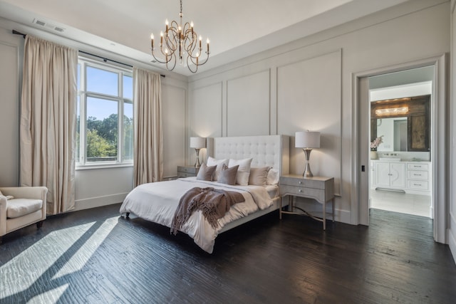 bedroom featuring a notable chandelier, dark wood-type flooring, and ensuite bath