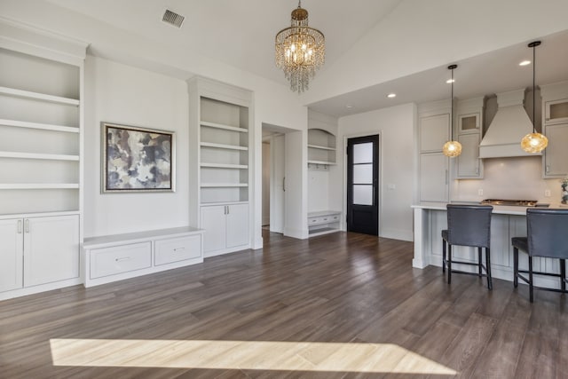 living room with built in shelves, high vaulted ceiling, dark hardwood / wood-style floors, and an inviting chandelier