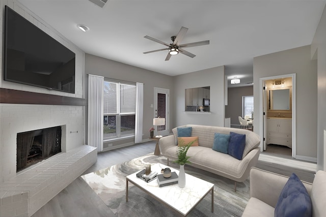 living room featuring light hardwood / wood-style floors, a brick fireplace, ceiling fan, and sink