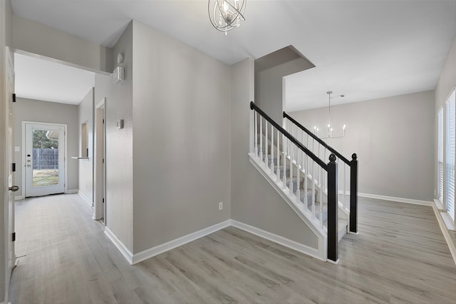 stairs featuring wood-type flooring and an inviting chandelier