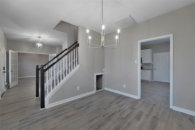 unfurnished dining area featuring a chandelier and light hardwood / wood-style flooring