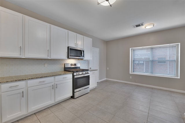 kitchen featuring decorative backsplash, white cabinets, stainless steel appliances, and light tile patterned floors