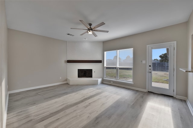 unfurnished living room featuring light hardwood / wood-style flooring, a brick fireplace, a wealth of natural light, and ceiling fan