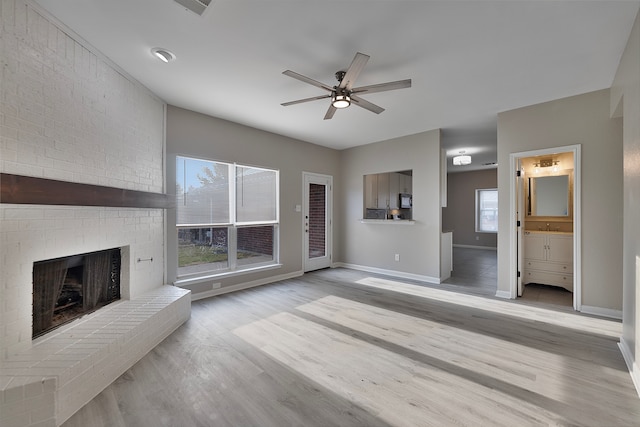 unfurnished living room featuring ceiling fan, light hardwood / wood-style flooring, and a brick fireplace