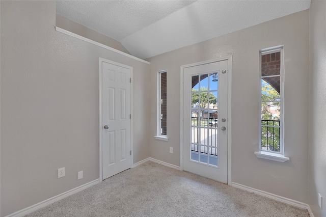 entryway with a textured ceiling, light colored carpet, and vaulted ceiling