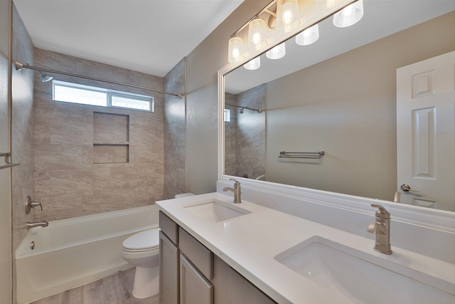 full bathroom featuring hardwood / wood-style floors, tiled shower / bath combo, toilet, and vanity