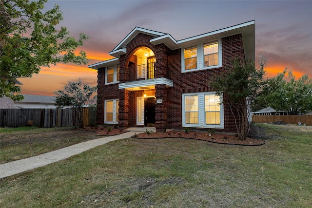 view of front of home with a balcony and a lawn