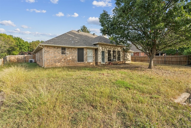 rear view of house featuring central AC and a yard