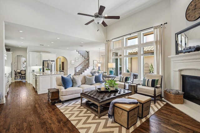 living room with ceiling fan, light hardwood / wood-style floors, and a towering ceiling