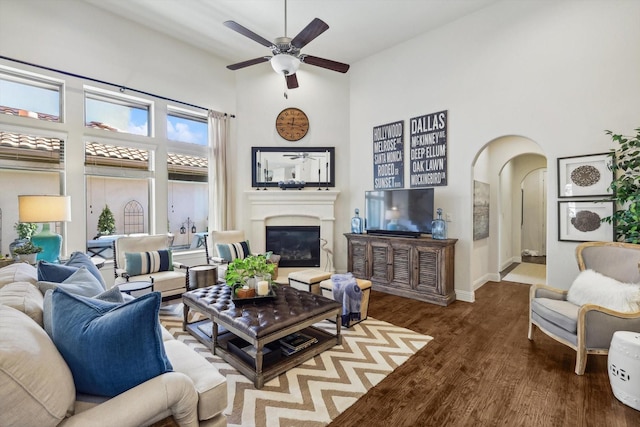 living room featuring ceiling fan, wood-type flooring, and a high ceiling