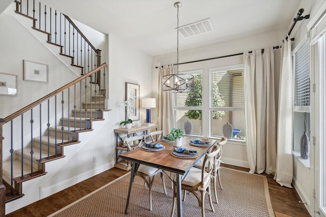 dining room with dark wood-type flooring and a notable chandelier