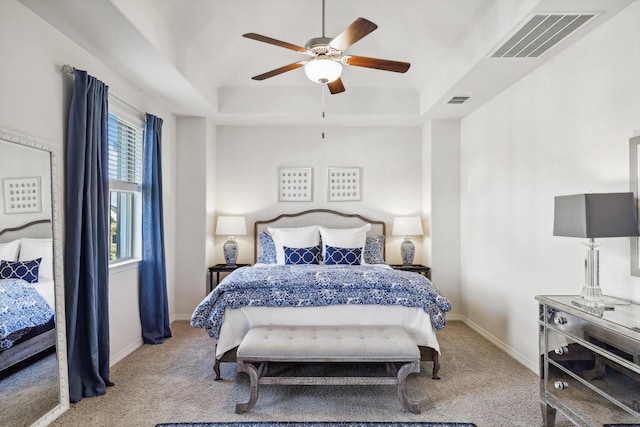 bedroom with ceiling fan, light carpet, and a raised ceiling