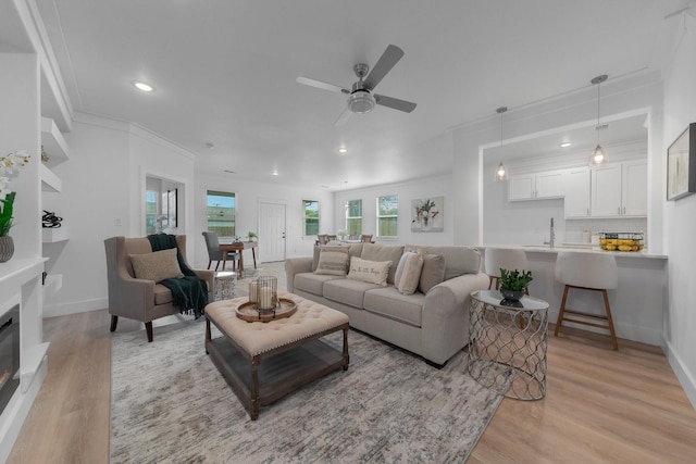 living room with ceiling fan, light hardwood / wood-style flooring, and crown molding