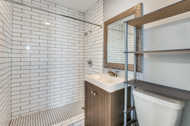 bathroom with toilet, vanity, and a tile shower