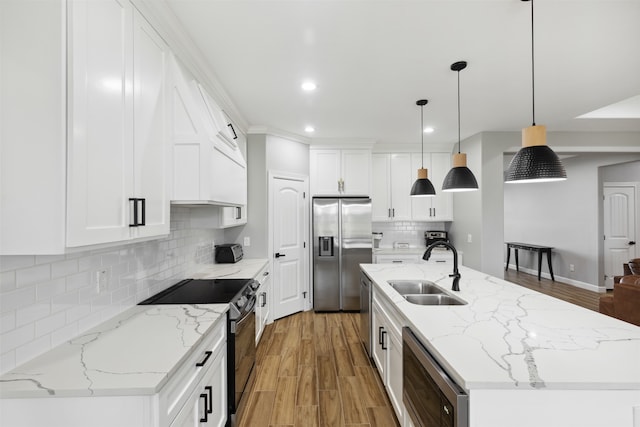 kitchen featuring appliances with stainless steel finishes, sink, pendant lighting, white cabinets, and a kitchen island with sink