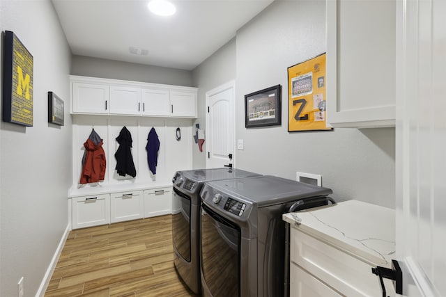 washroom with light hardwood / wood-style floors, washing machine and dryer, and cabinets