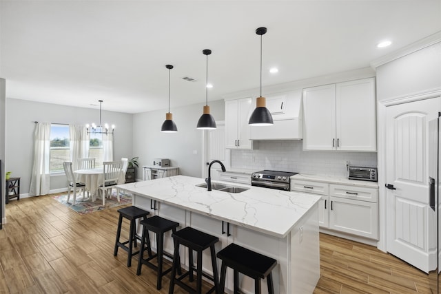 kitchen featuring white cabinetry, a kitchen island with sink, stainless steel electric range oven, light hardwood / wood-style floors, and sink