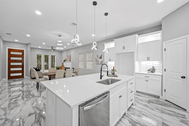 kitchen with hanging light fixtures, sink, stainless steel dishwasher, and white cabinets