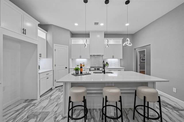 kitchen with white cabinetry, sink, a center island with sink, and pendant lighting