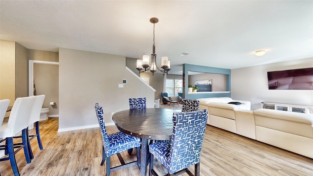 dining room with light hardwood / wood-style floors and a notable chandelier