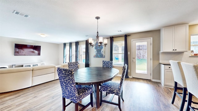 dining space with a notable chandelier, a textured ceiling, a wealth of natural light, and light wood-type flooring