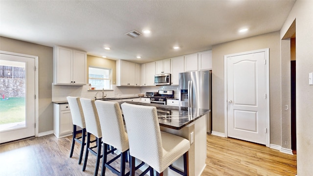 kitchen featuring a breakfast bar area, white cabinets, stainless steel appliances, and a kitchen island