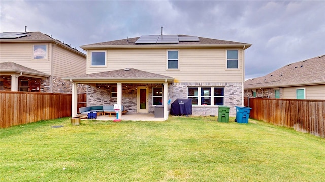 rear view of property featuring a patio, solar panels, and a yard