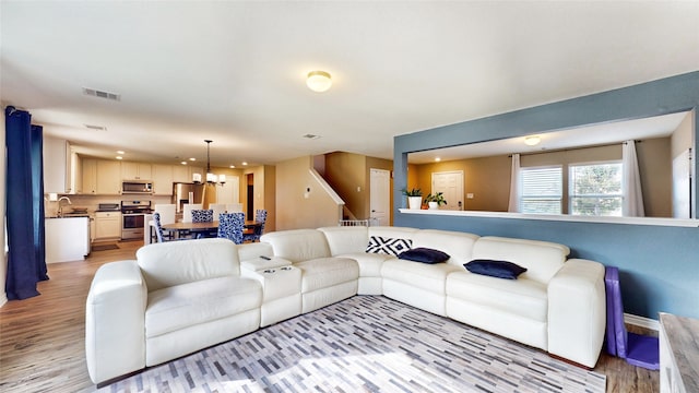 living room featuring light hardwood / wood-style floors, an inviting chandelier, and sink