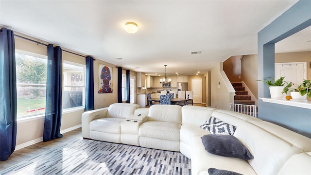 living room featuring a healthy amount of sunlight, wood-type flooring, and a chandelier