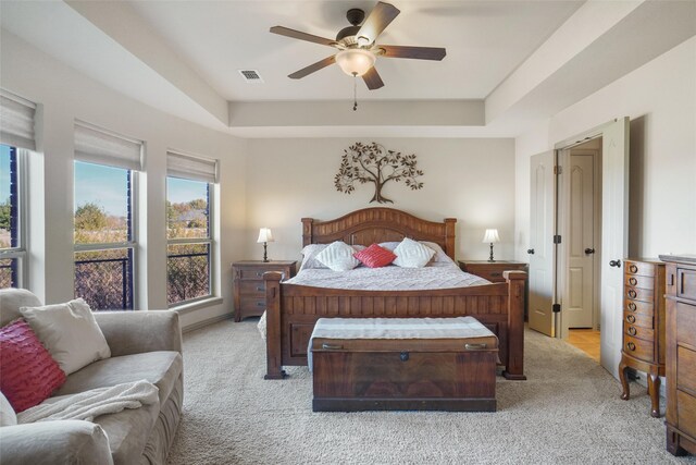 carpeted bedroom featuring ceiling fan and a tray ceiling