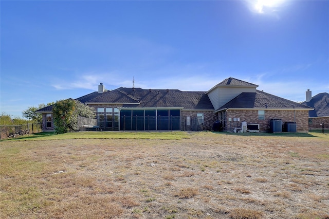 rear view of house with a lawn, a sunroom, and central air condition unit