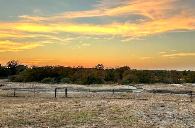 yard at dusk featuring a rural view