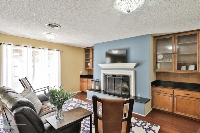 living room featuring a tiled fireplace, dark hardwood / wood-style flooring, and a textured ceiling