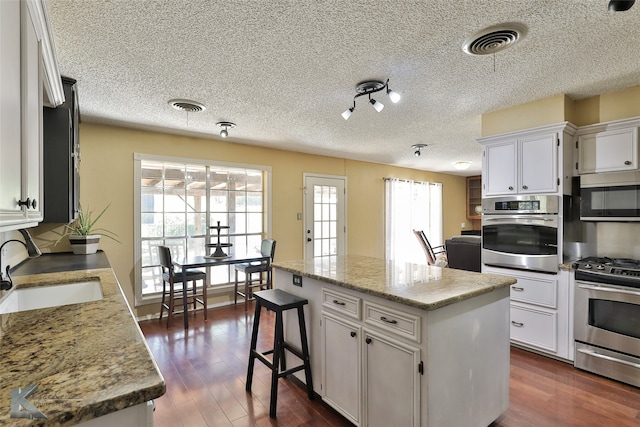 dining space featuring a tile fireplace, french doors, a textured ceiling, and hardwood / wood-style flooring