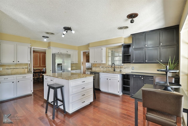 kitchen featuring a center island, white cabinets, stainless steel appliances, and sink