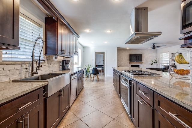 kitchen with island exhaust hood, a healthy amount of sunlight, stainless steel appliances, and backsplash