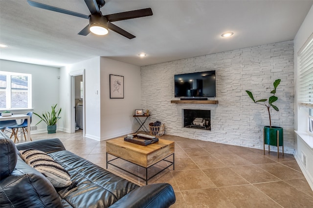 tiled living room featuring ceiling fan and a fireplace