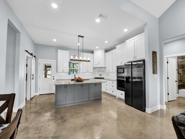 kitchen featuring a barn door, white cabinets, appliances with stainless steel finishes, a center island, and decorative light fixtures