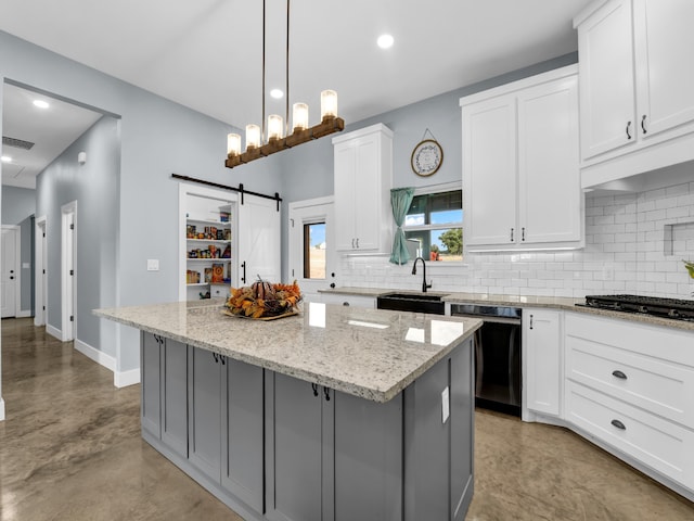 kitchen with black dishwasher, a sink, a kitchen island, and white cabinets