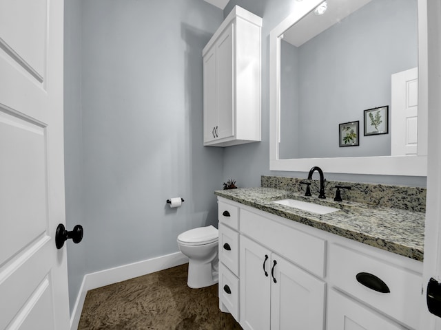 half bathroom with toilet, baseboards, and vanity