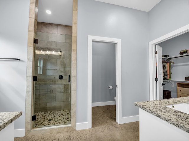 bathroom with recessed lighting, vanity, baseboards, a spacious closet, and a shower stall