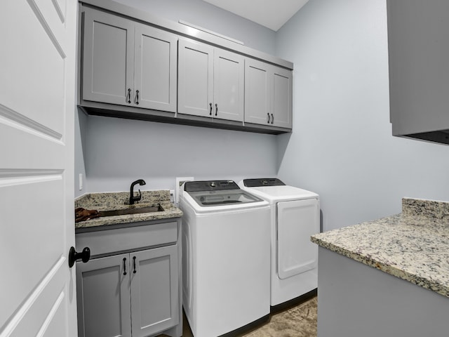 clothes washing area with cabinet space, a sink, and washing machine and clothes dryer