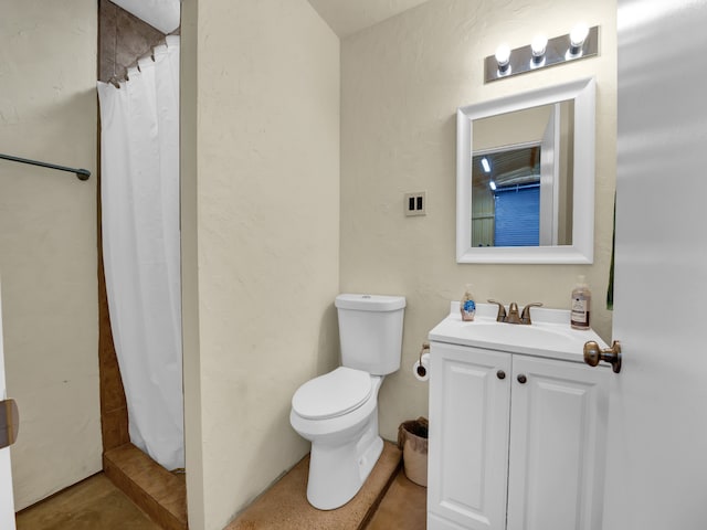 bathroom featuring a stall shower, a textured wall, vanity, and toilet